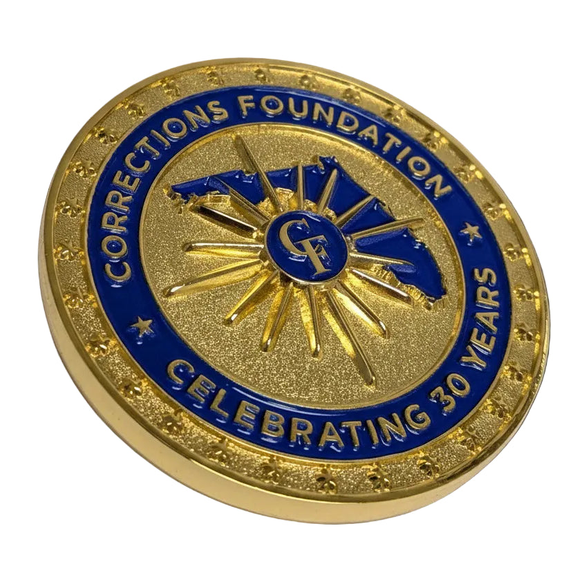 Gold and blue commemorative coin for Corrections Foundation celebrating 30 years on a light gray background